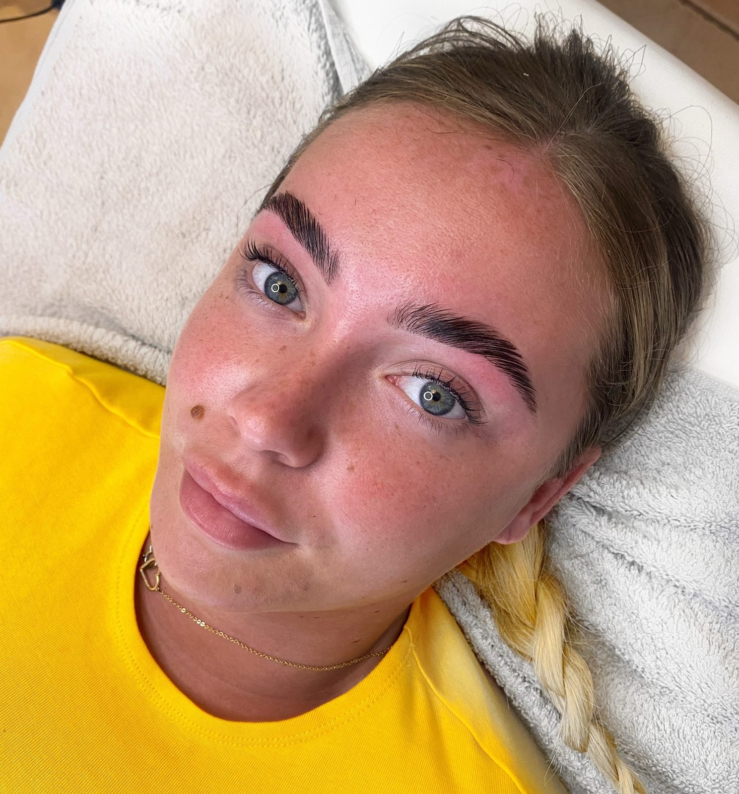 Defined, natural brows on a client in a yellow top